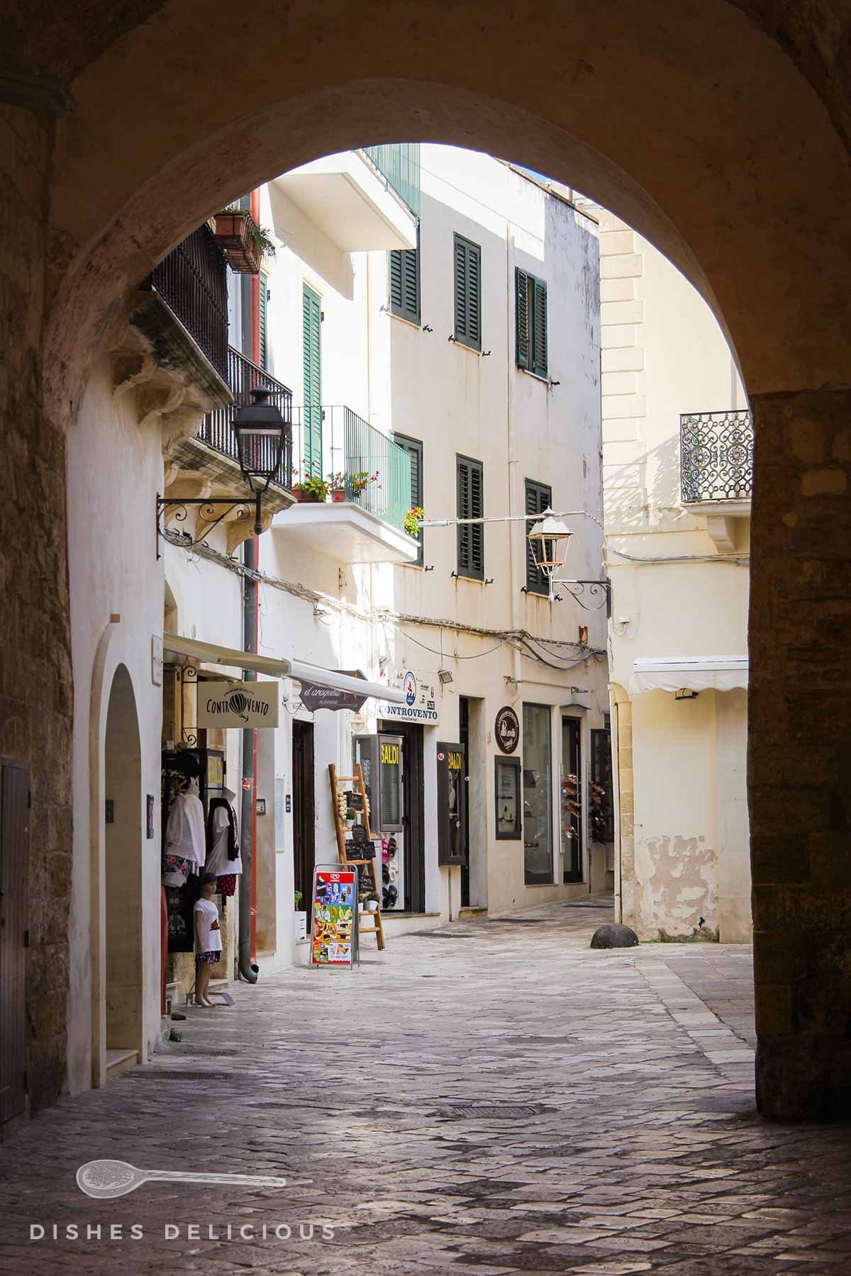 Tor am Eingang zur Altstadt von Otranto, Geschäfte laden zum Shoppen ein.