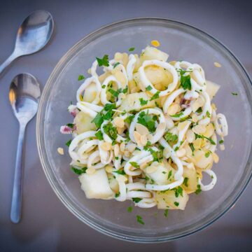 Eine Schüssel mit Calamari-Salat mit Melone, Mandelblättchen und gehackter Petersilie.