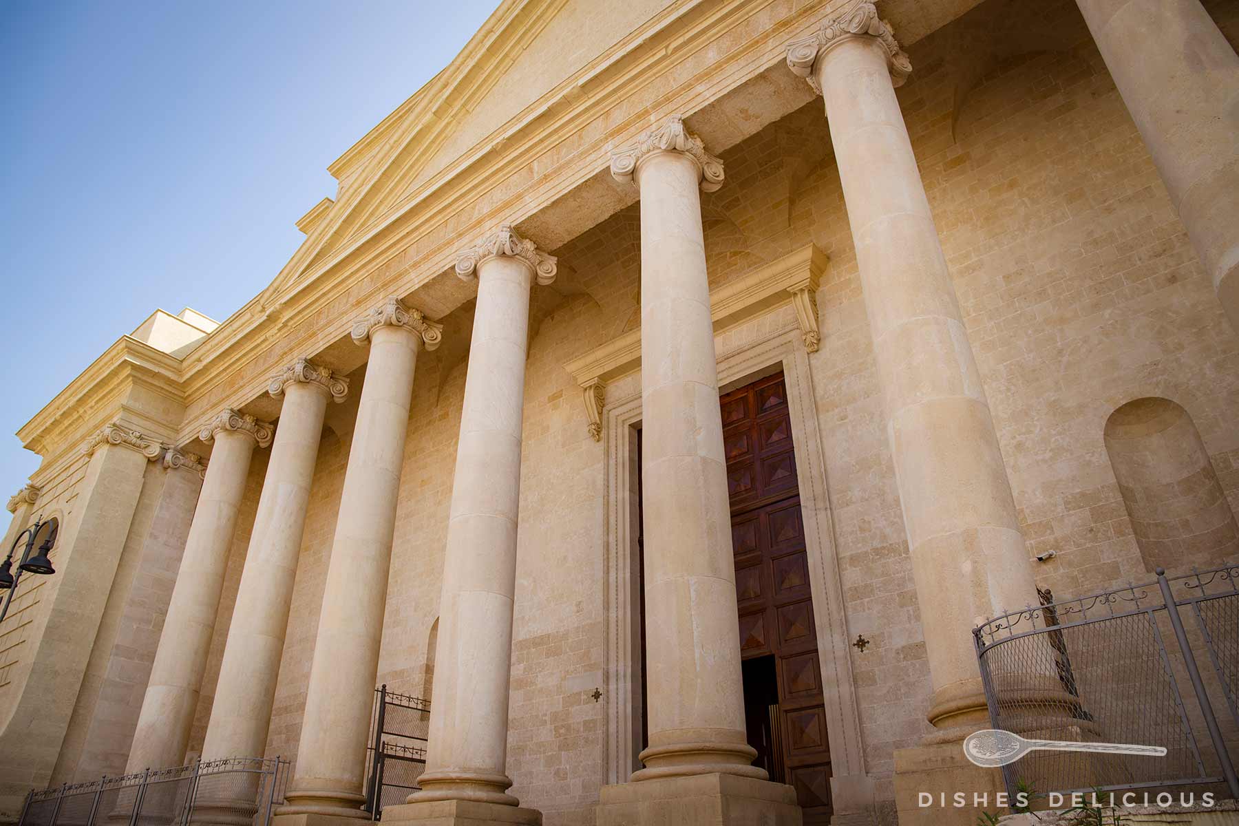 Ansicht des Haupteingans des Doms von Massafra: Dicke Säulen tragen die in neoklassischer Architektur erbaute Kirche.