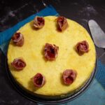 Ein neapolitanischer Kartoffelkuchen, dekoriert mit Rosen aus Schinken, bereit zum Anschneiden.