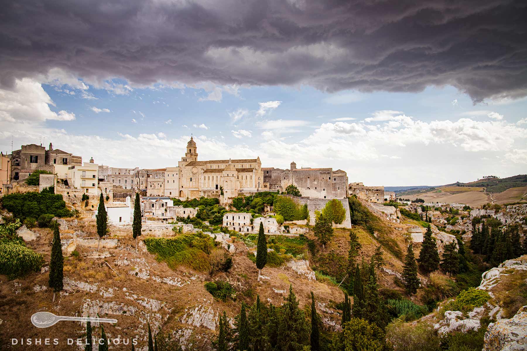 Die Kathedrale und Schlucht von Gravina, über der ein Gewitter mit dunklen Wolken aufzieht