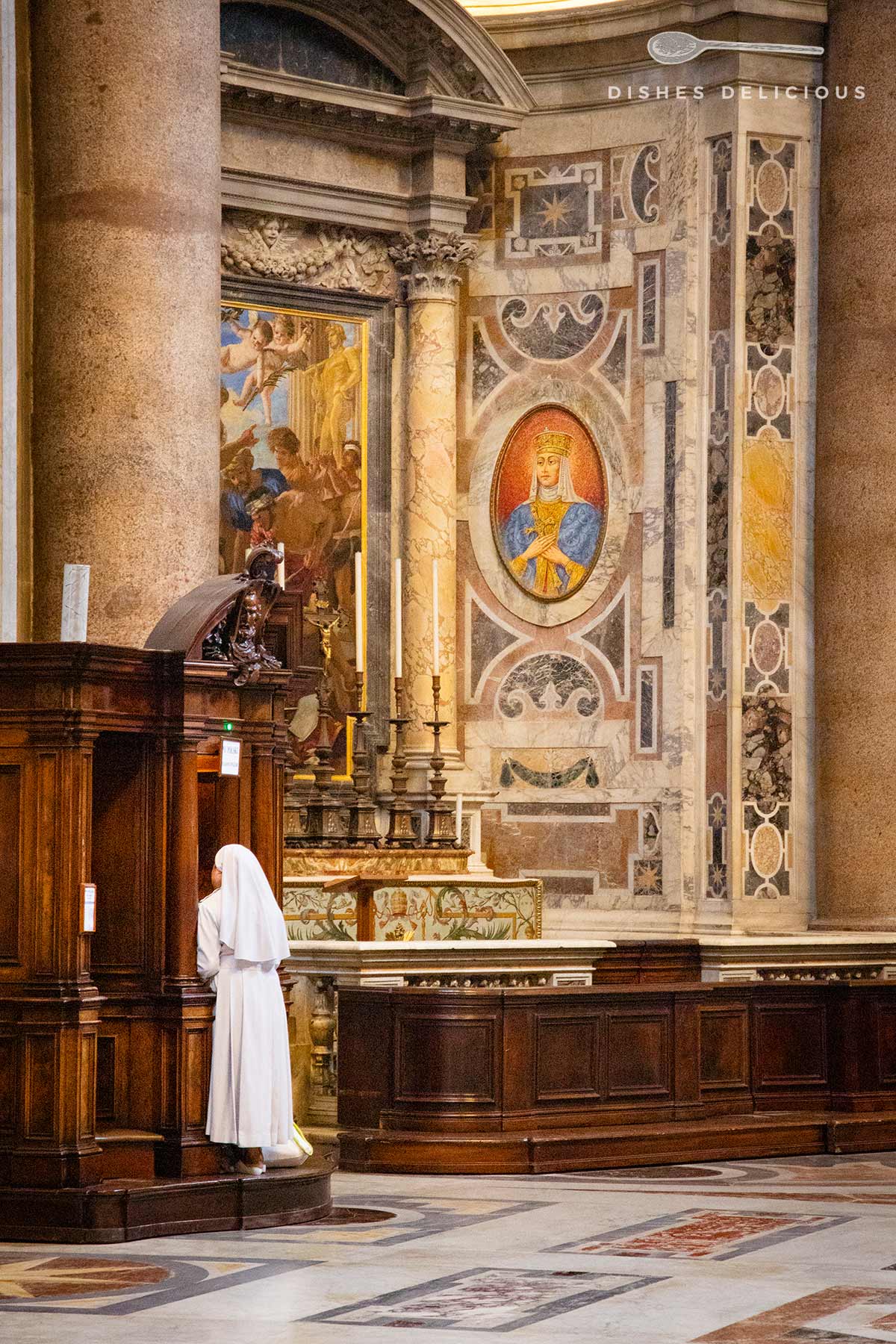 Eine Nonne steht an einem Beichtstuhl in der Peterskirche, im Hintergrund ein mit Marmor und Fresken verzierter Altar in einer Apsis.