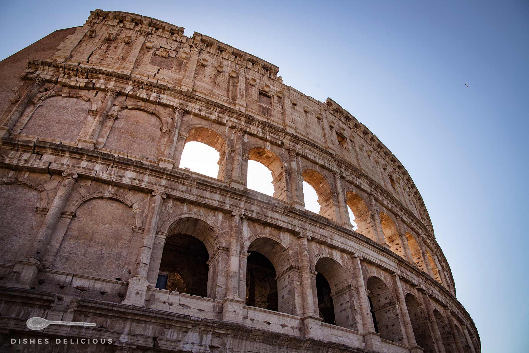 Die Fassade des Kolosseums in Rom: drei Etagen mit Bögen, unterteilt von dorischen, ionischen und korinthischen Säulen.