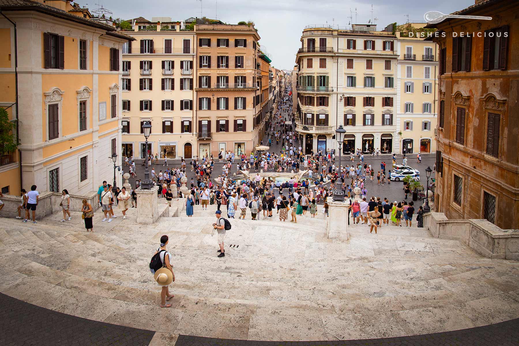 Die Spanische Treppe in Rom mit vielen Touristen, die auf den Stufen und im darunterliegenden Platz unterwegs sind.