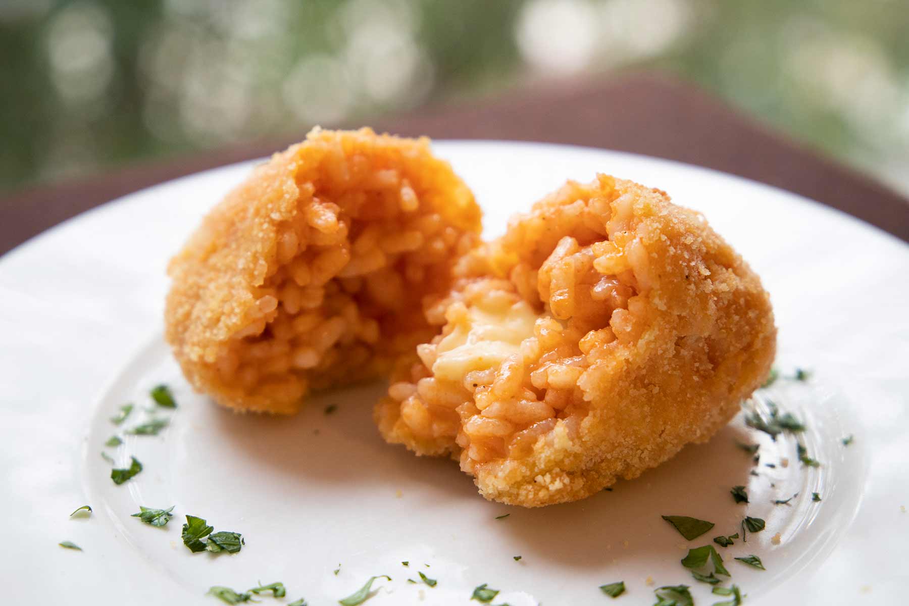 Eine in der Mitte halbierte Reiskrokette "Suppli al telefono"