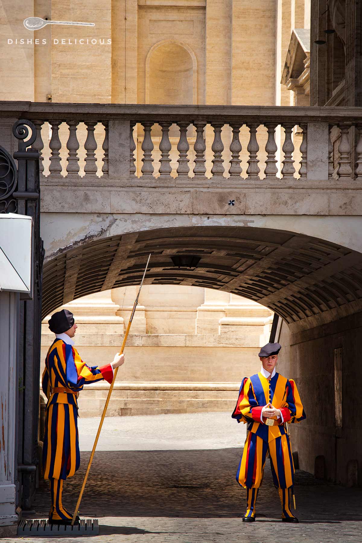 Zwei Wachen der Schweizer Garde in bunter Uniform wachen an einem Eingangstor vor dem Petersdom.