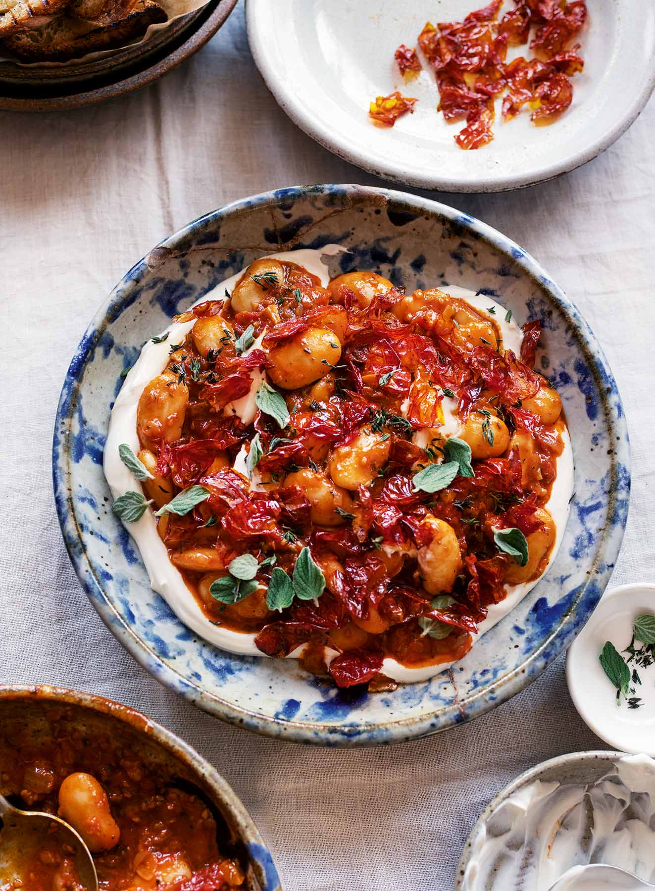 Ottolenghi Comfort: Ein Teller weeiße Bohnen mit gerösteten Kirschtomaten auf Joghurt.