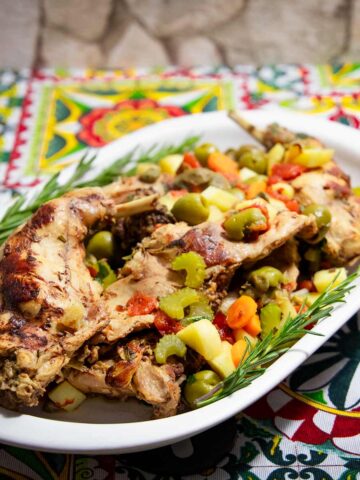 Ein Servierteller mit Kaninchenfleisch auf Ragusa-Art mit Gemüse.