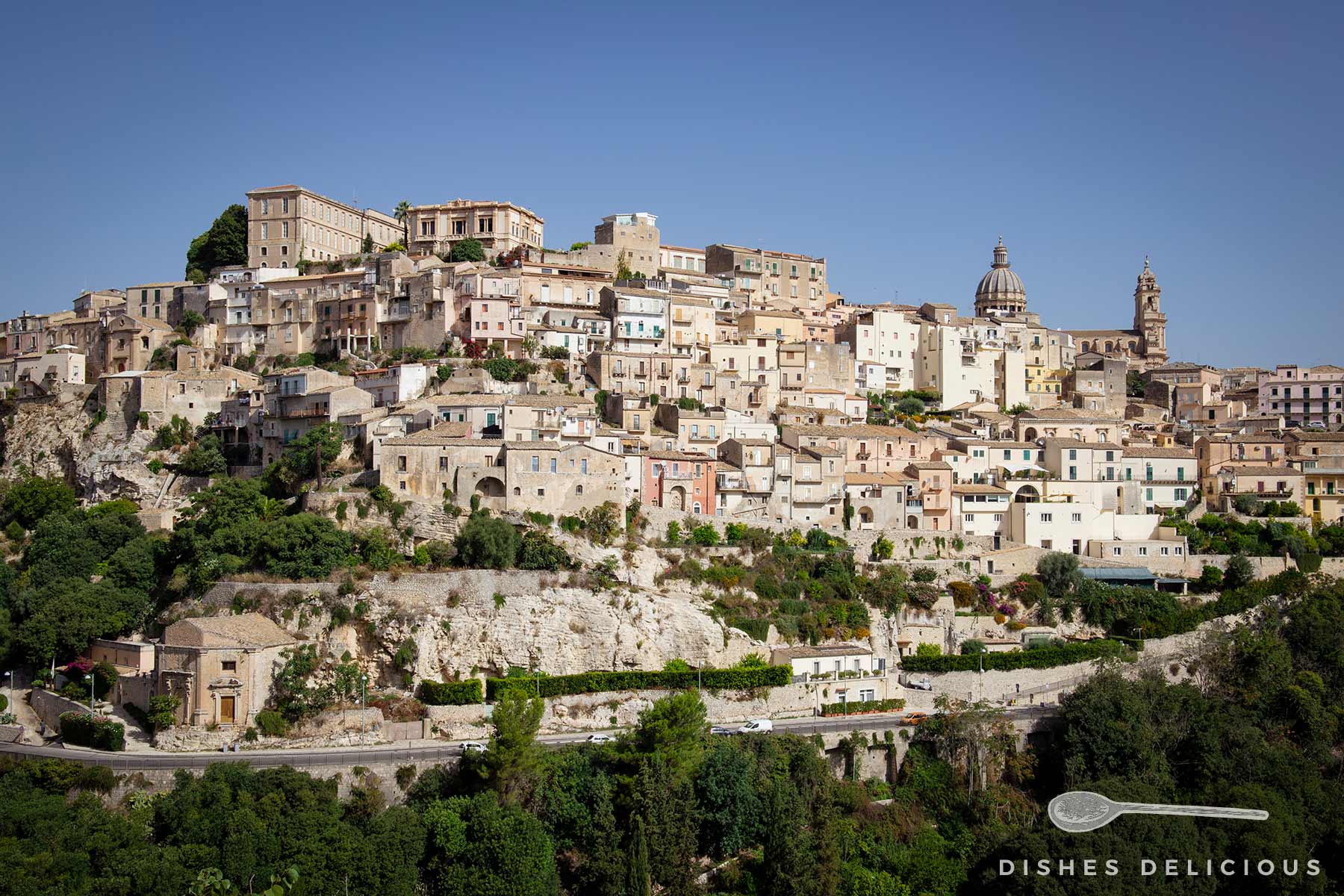 Panoramaansicht von Ragusa Ibla auf Sizilien. Die Stadt erstreckt sich auf einem Hügel und ist geprägt von einer dichten Ansammlung von Gebäuden in hellen, erdigen Farben.