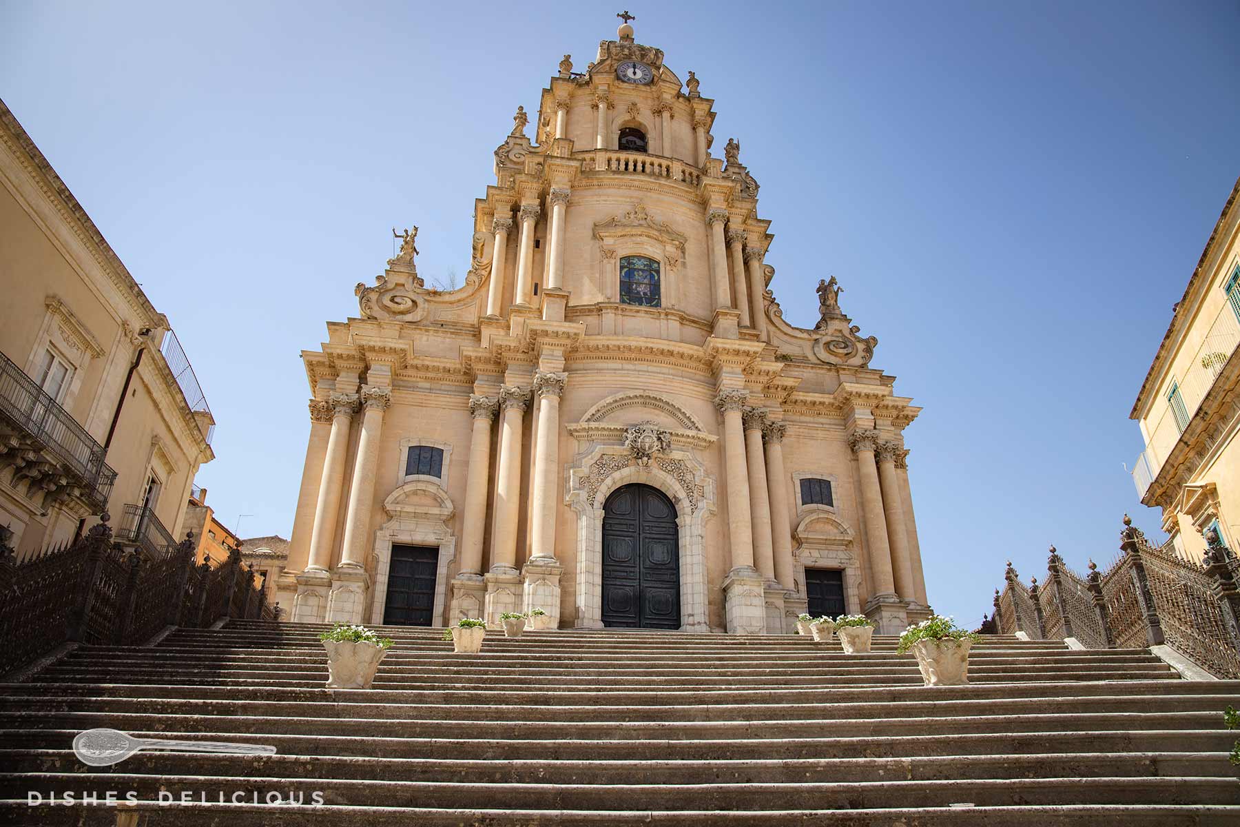 Kathedrale San Giorgio in Ragusa Ibla, Sizilien. Die Fassade der Sehenswürdigkeit ist reich verziert mit Säulen, Statuen und kunstvollen Details. Eine breite Treppe führt hinauf zur Kirche.
