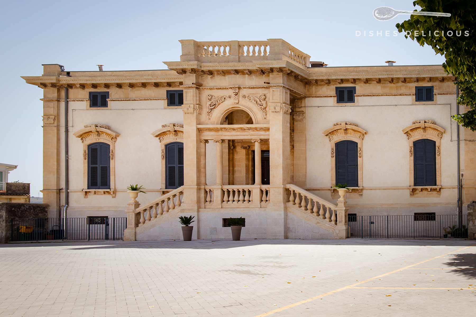 Villino Arezzo mit einer eleganten, klassischen Fassade. Der Hof vor dem Gebäude ist mit hellgrauen Steinen gepflastert.