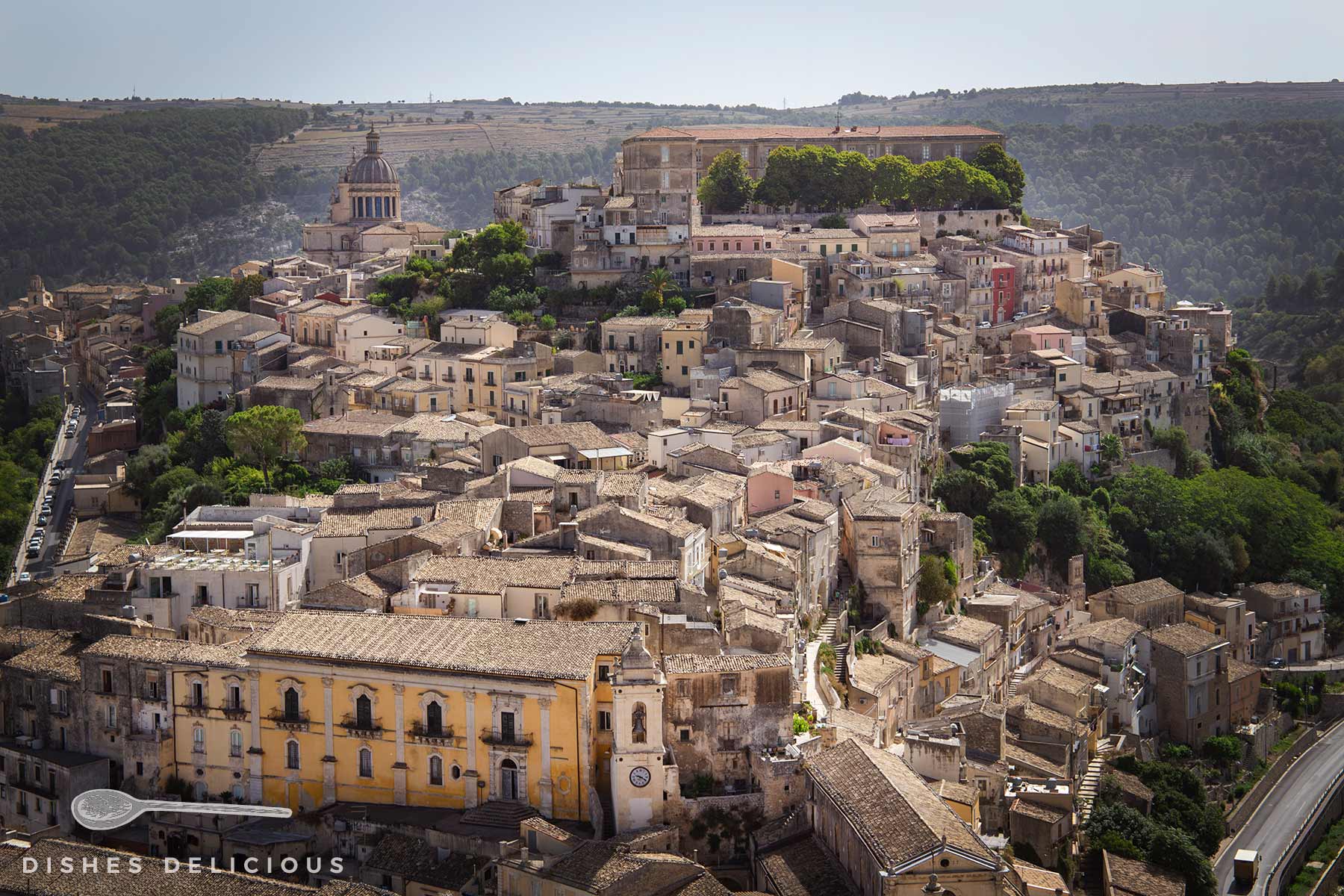 Panorama von Ragusa Ibla mit den vielen alten Häusern, die dicht an dicht den Hügel hinaufgebaut sind. An der Spitze sind der Dom und ein altes Militärgebäude zu sehen.