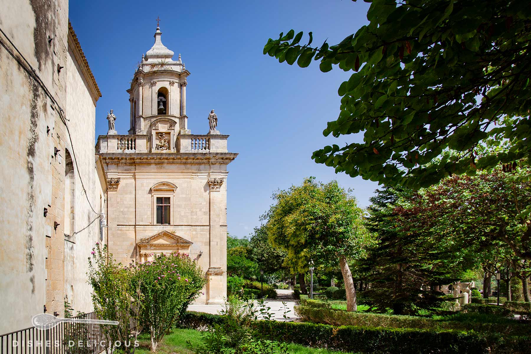Kirche San Giacomo Apostolo im Giradino Ibleo. Rund um die Kirche mit einem Glockenturm erstreckt sich der Park mit Bäumen, Hecken und Spazierwegen