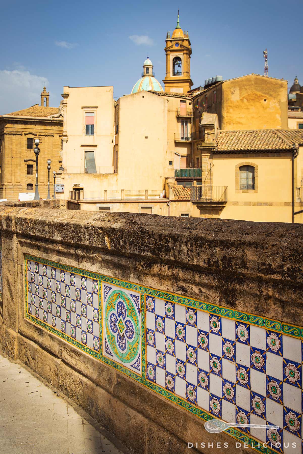 Brücke San Francesco mit bunten Kacheln in Caltagirone, im Hintergrund gelbe Gebäude und Kirchturm mit Kuppel