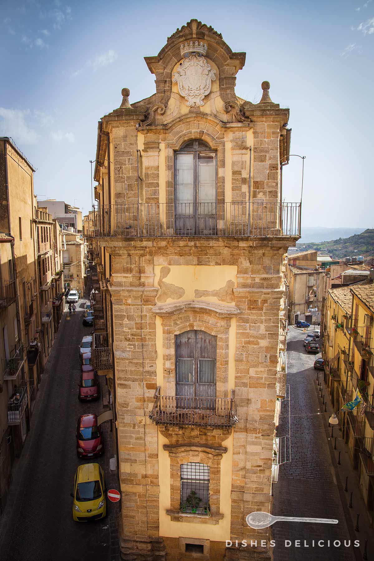 Barockes dreistöckiges Gebäude mit verzierten Fenstern und Balkonen in einer engen Straße in Caltagirone, Sizilien.