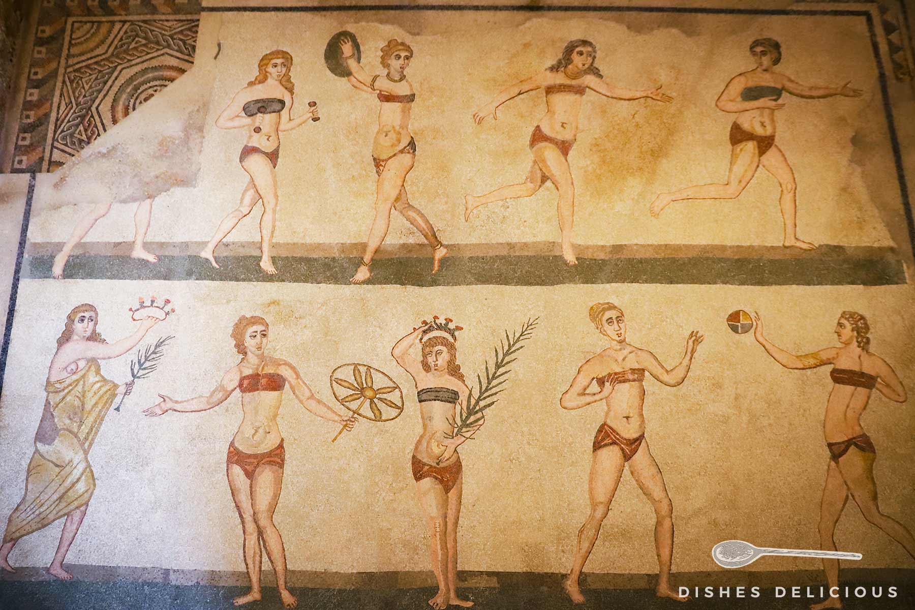 Antike Mosaikdarstellung von Frauen in Bikinis bei sportlichen Aktivitäten in der Villa Romana del Casale.