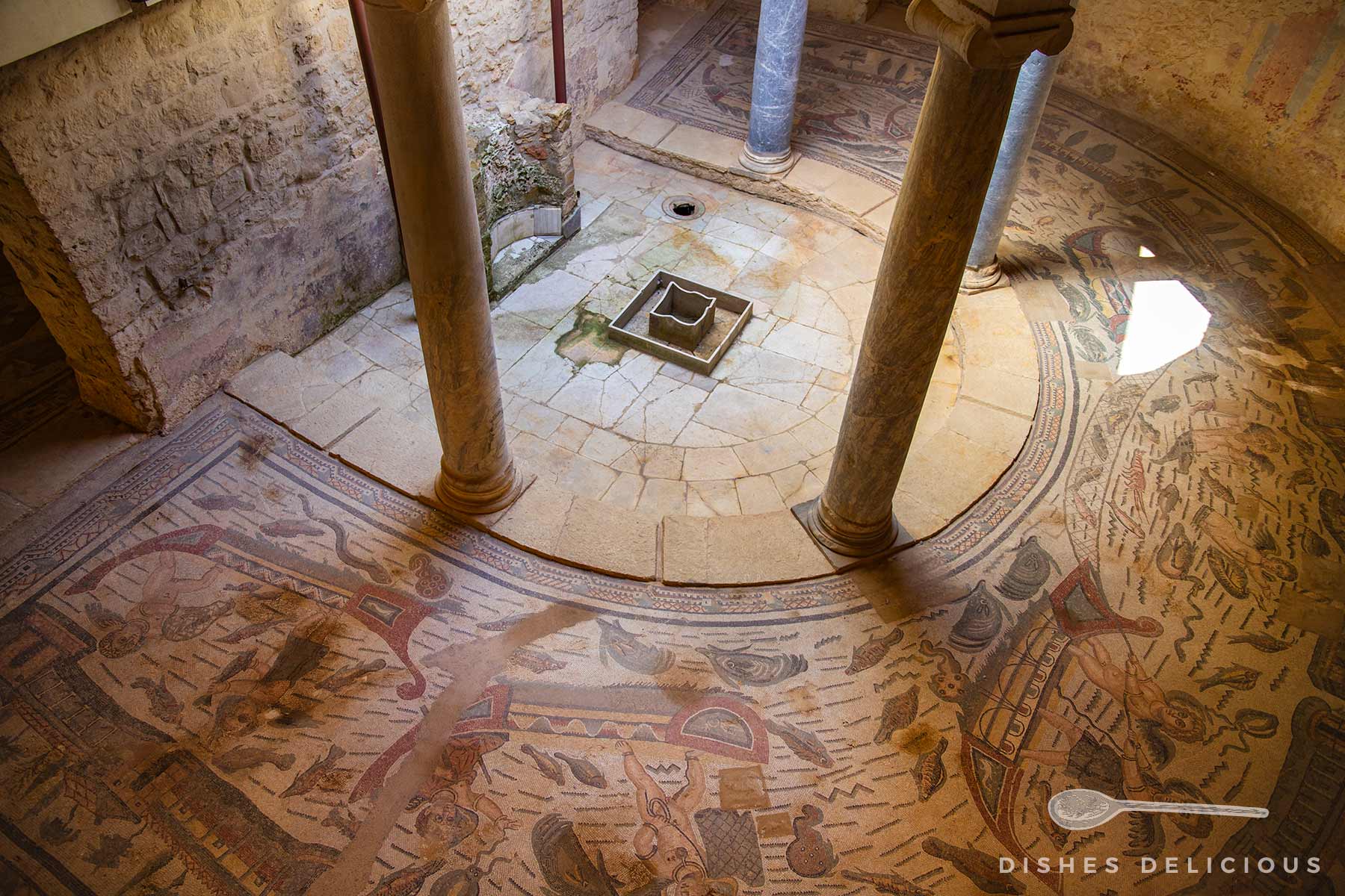 Mosaikboden mit antiken Darstellungen im Peristyl der Villa del Casale, umgeben von Säulen und Steinmauern.
