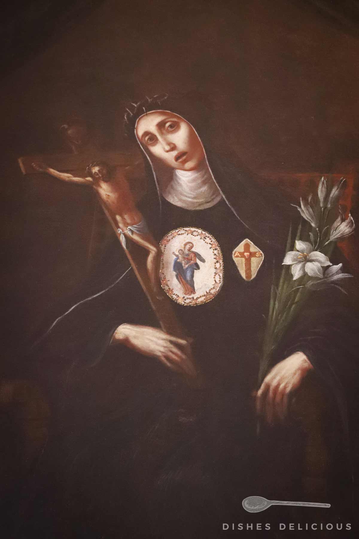 Gemälde der Heiligen Isabella Tomasi aus Agrigento in schwarzem Habit mit weißen Lilien in der linken Hand, hält ein Kruzifix in der rechten Hand, auf der Brust zwei Medaillons mit religiösen Darstellungen.