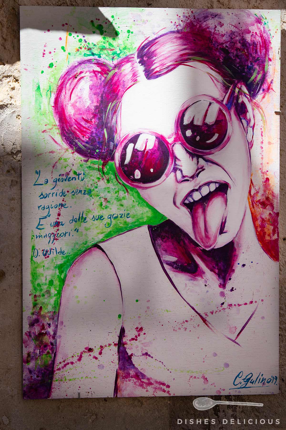 Street-Art mit einer Frau mit pinken Haaren, grünen Farbspritzern und einem Zitat von Oscar Wilde in blauer Schrift.