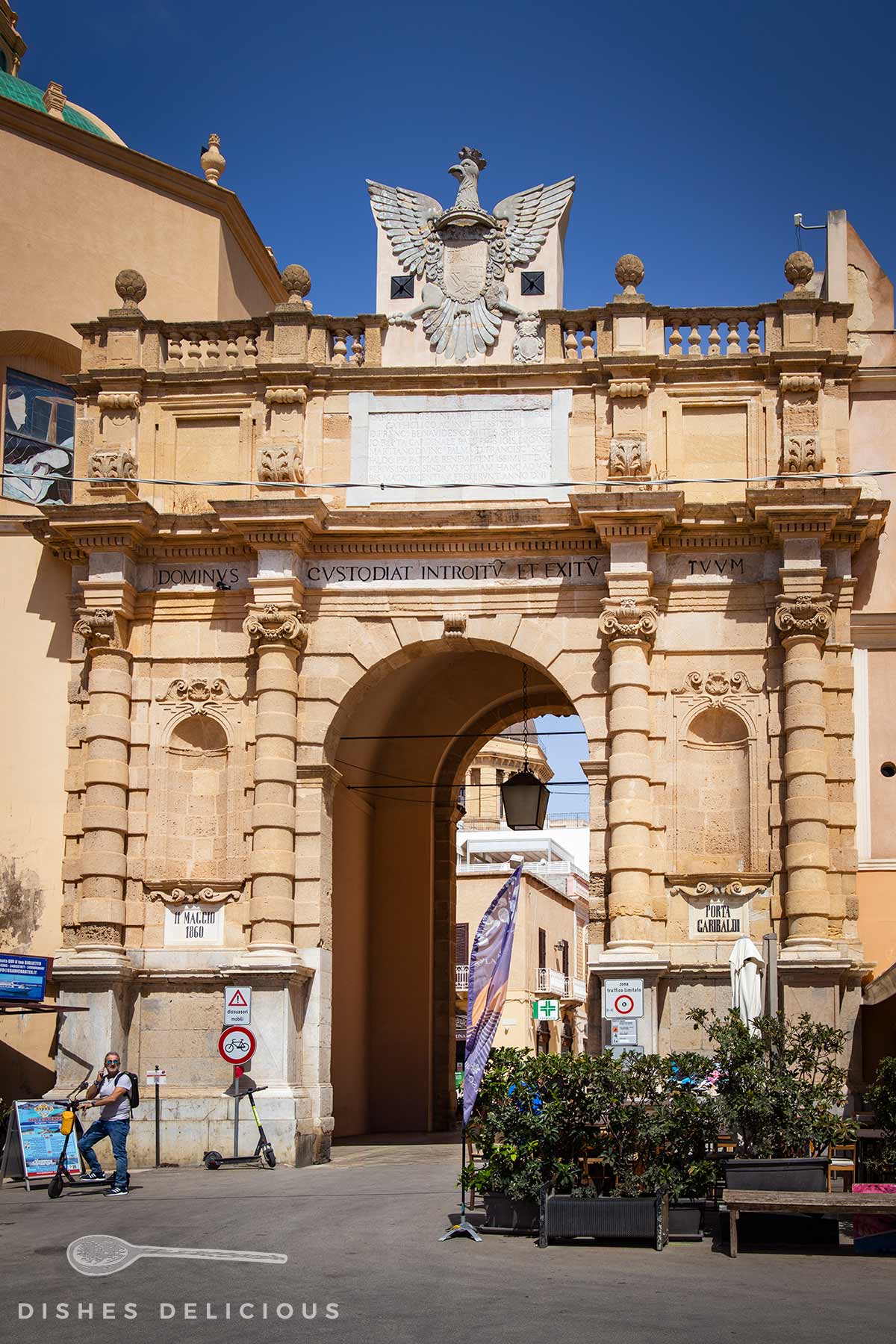 Barockes Stadttor Porta Garibaldi in Marsala mit Säulen, Balustrade und Wappenskulptur, Durchgang mit Laterne und Straßenschildern.