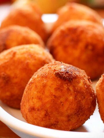 Frittierte, runde Arancini auf einem weißen Teller