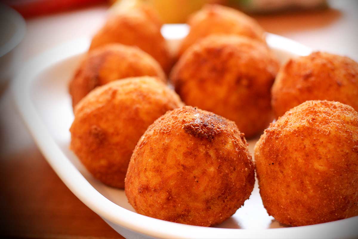 Frittierte, runde Arancini auf einem weißen Teller