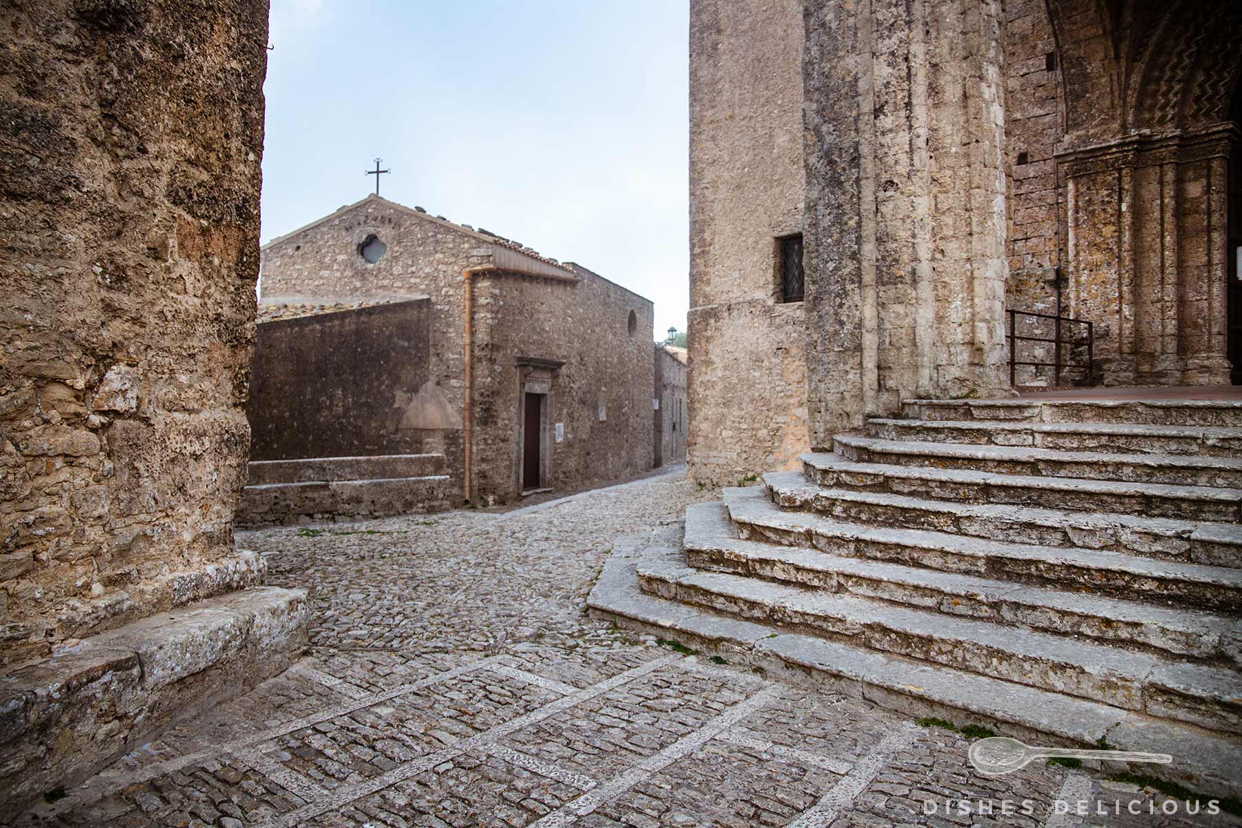 Steinerne Treppe der Kathedrale und eine kleine Kapelle an einer mittelalterlichen Kopfsteinpflasterstraße in Erice.
