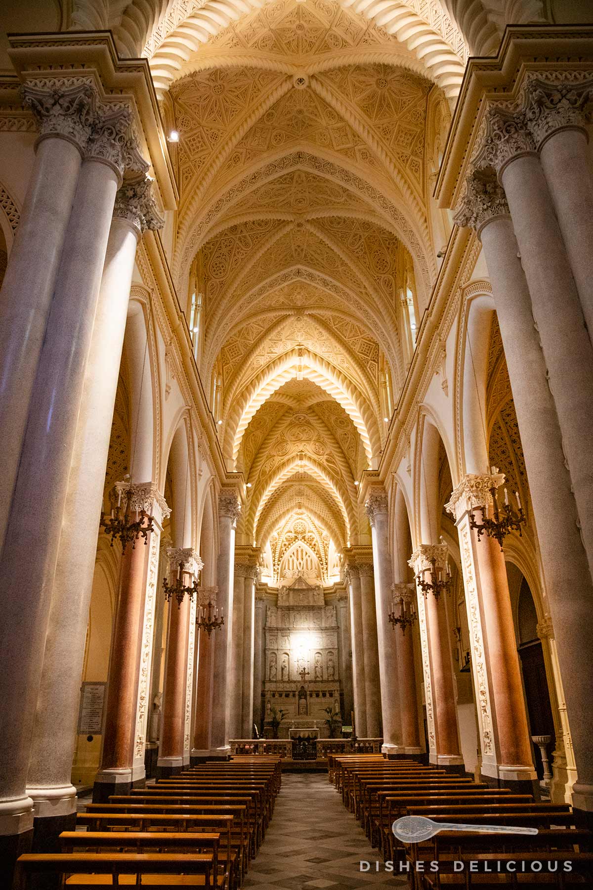Innenraum der Kathedrale von Erice mit hohen Säulen, gewölbter Decke und Holzbänken, Blick zum Altar.