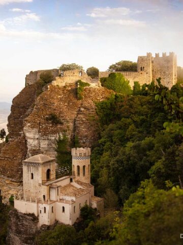 Torretta Pepoli: Kleines Schloss mit zwei Türmen auf steinigem Felsen, umgeben von dichtem Grün.