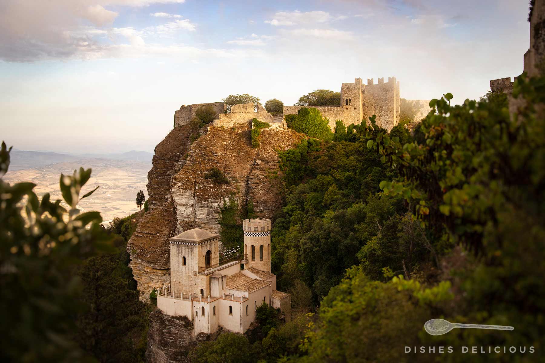 Torretta Pepoli: Kleines Schloss mit zwei Türmen auf steinigem Felsen, umgeben von dichtem Grün.